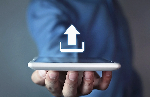 Symbolbild - Auf diesem sieht man eine Hand die ein Tablet hält und darüber ist ein Symbol für Download abgebildet.