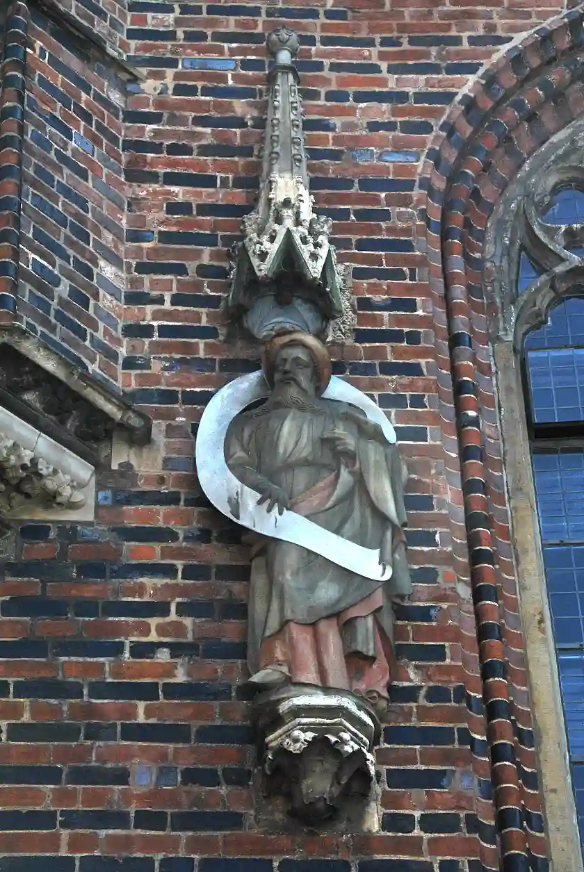 Plato -ursprünglich Prophet Hesekil - trägt einen tief in den Nacken geschobenen Hut, der eine breite Krempe hat. Über seinem Gewand hat er einen Mantel an, den er mit der linken Hand in Höhe seiner Brust gerafft hält. Mit der Rechten umfasst er das große Spruchband, das sich hinter seinem Kopf um seinen Körper schlingt.