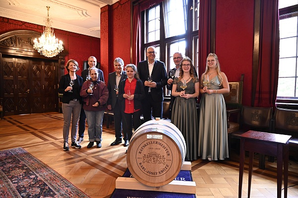 Bürgermeister Andreas Bovenschulte (Mitte), ein Fass Erdener Treppchen 2022 und weitere an der Entstehung des Senatsweins Beteiligte bei der Vorstellung des neuen Jahrgangs.