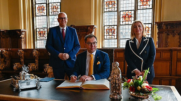 Eintrag in das Goldene Buch: Botschafter Oleksii Makeiev (sitzend), Bürgermeister Andreas Bovenschulte und Generalkonsulin Iryna Tybinka.